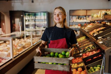 Gururlu ve hevesli bir çalışan marketlerde canlı üretim yapan bir sepet taze limon sergiliyor.