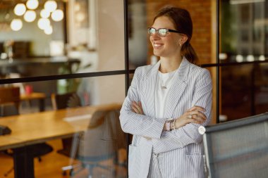 Profesyonel bir kadın, modern bir ofis alanında, gerçek liderliği somutlaştırırken kendine güvenerek gülümser.