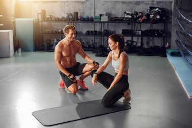 Kişisel antrenör, modern bir spor salonunda çeşitli fitness egzersizleri yapan bir kadına özenle yardımcı olur.