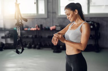 Formda bir kadın modern bir spor salonunda yoğun bir antrenman yaptıktan sonra dikkatli bir şekilde kendini kontrol eder.