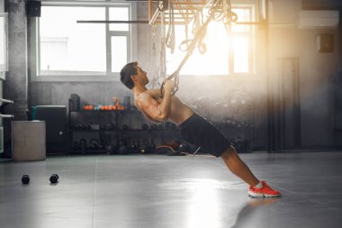 Geniş, iyi donanımlı bir spor salonu ortamında direniş bandı egzersizleri yapan aktif ve formda bir birey.