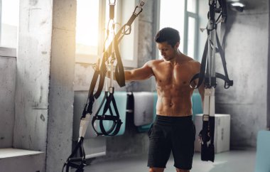Parlak, modern bir fitness stüdyosunda spor aletlerini etkin güç eğitimi için kullanan odaklanmış bir birey.