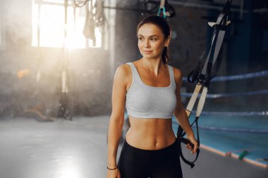 Parlak ve hayat dolu bir spor salonunda, kendine güvenen bir kadın özgüvenli bir şekilde antrenmanına hazırlanır.
