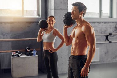 Enerjik ve motive edici bir egzersiz sahnesi bir erkek ve dişi ikiliyi ağırlıklarla etkili bir şekilde egzersiz yaparken gösteriyor.