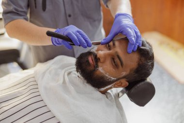 Son derece yetenekli bir berber, modern bir berber dükkanındaki müşteriye son derece rahatlatıcı ve tatmin edici bir tıraş sağlar.