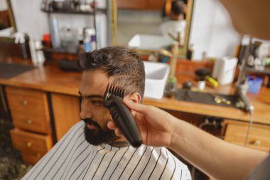 Çok yetenekli bir berber modern ve cazip bir berber dükkanında ustaca saç kesimi sağlıyor.