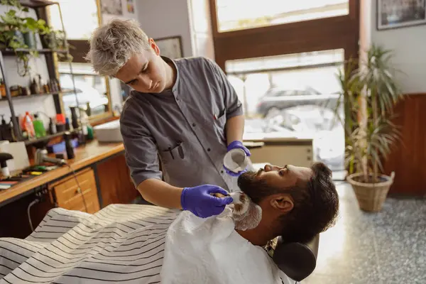 Son derece yetenekli ve profesyonel bir berber, modaya uygun bir berber dükkanındaki tatmin edici bir müşteriye rahatlatıcı bir tıraş sağlıyor.