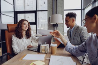 Çeşitli profesyonellerle verimli bir iş toplantısı. Parlak ve modern bir ofiste fikirleri tartışıyorlar.