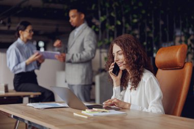 Çeşitli yetenekli profesyonellerden oluşan bir grup, modern ve iyi tasarlanmış bir ofis ortamında etkili bir işbirliği içinde çalışıyor.