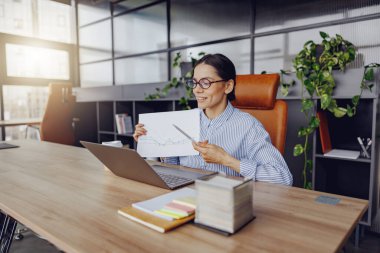Kararlı ve odaklanmış bir iş kadını modern bir ofis alanında önemli belgeler sunuyor.