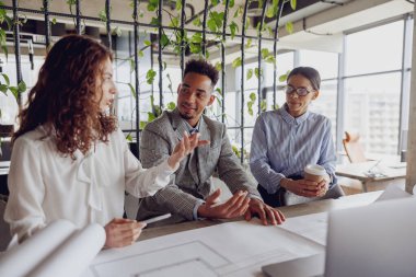 Çeşitli bir ekip, şık ve yenilikçi bir çalışma alanında yaratıcı bir toplantı sırasında aktif olarak dinamik bir tartışmaya girişir.
