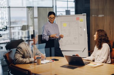 Çeşitli bir ekip, modern bir ofiste son derece verimli bir sunum sırasında aktif olarak stratejileri tartışır.