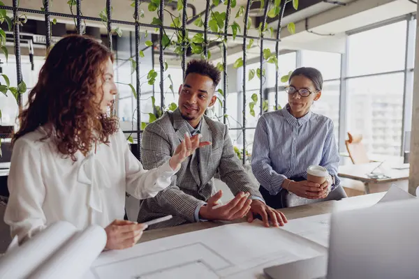 Çeşitli bir ekip, şık ve yenilikçi bir çalışma alanında yaratıcı bir toplantı sırasında aktif olarak dinamik bir tartışmaya girişir.