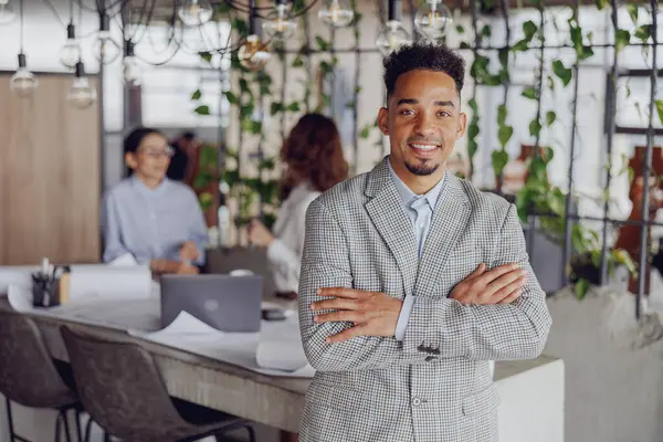 Şık ve profesyonel bir birey, canlı, bitkisel ve şık bir çalışma alanında güven içinde poz verir.