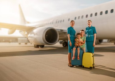 Neşeli bir aile, havaalanındaki arkadaş canlısı havayolu ekibiyle birlikte seyahat heyecanlarını paylaşarak poz veriyor.