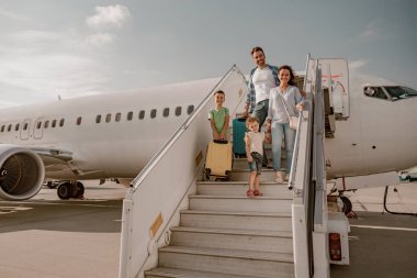 Neşeli ve mutlu bir aile heyecan verici tatil maceralarına hevesle hazır büyük bir uçaktan iniyor.