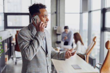 Modern bir ofiste başarılı bir işadamı telefonda önemli konuları tartışır, çalışma alanı tasarımını ön plana çıkarır