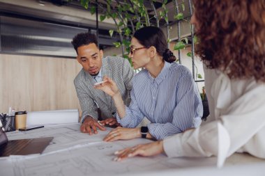 Bir grup profesyonel, parlak ve modern ofis ortamında stratejik planları tartışır.