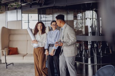 Çeşitli profesyonellerden oluşan bir grup modern ofis ortamındaki planlarla ilgili derin bir tartışma yürütüyor.