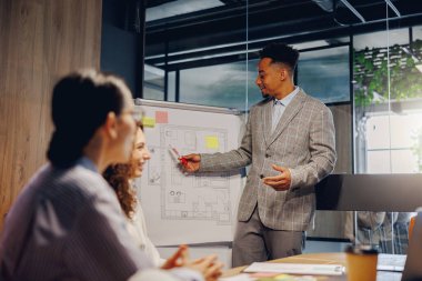 Nitelikli bir profesyonel, modern bir çalışma alanında yapılan bir toplantı sırasında proje planlarını ayrıntılı olarak tartışır.