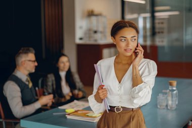 Profesyonel bir kadın telefonda konuşuyor, iş arkadaşlarıyla önemli iş görüşmeleri yapıyor.