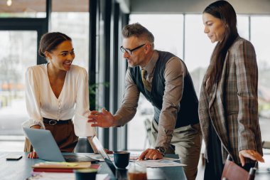 Takım üyeleri, şık ve ilham verici bir çalışma alanında dizüstü bilgisayarla verimli bir takım tartışmasına girişiyor.