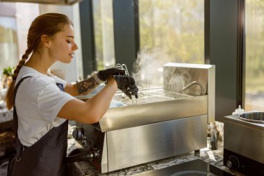 Odaklanmış bir barista, modern bir kafede espresso makinesi ekipmanı kullanır.
