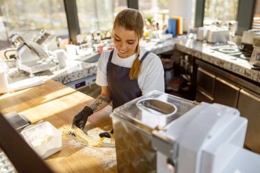 Odaklanmış bir kadın, etkileyici pişirme becerilerini ve yaratıcılığını sergileyerek, parlak bir mutfakta hamur hazırlıyor.