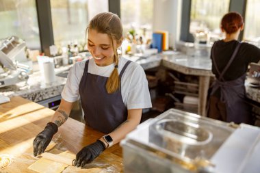 Tutkulu ve yetenekli bir fırıncı güzel, modern bir mutfak alanında lezzetli, ağız sulandırıcı ikramlar hazırlıyor.
