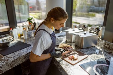 Parlak ve şık bir mutfakta genç bir aşçı titizlikle taze malzemeler hazırlıyor.