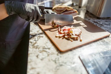 Yetenekli bir şef, ahşap bir tahta üzerinde çeşitli taze sebzeleri ve aromatik otları ustalıkla dilimler.