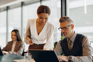 Modern ofis ortamında başarılı olmak için bir proje üzerinde çalışan kendini işine adamış bir takım.