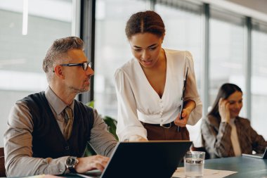 Çağdaş ofis ortamında etkin takım çalışması ve işbirliği sergileyen dinamik bir iş toplantısı