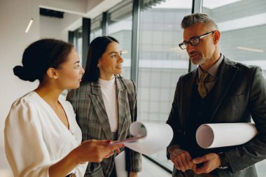 Proje planlarını modern bir ofiste tartışan profesyonellerden oluşan bir ekip işbirliğini teşvik ediyor.