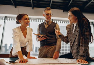 Değişik bir ekip enerjik bir ofiste iş birliği yapar, stratejileri tartışır ve başarı için yenilikçi fikirler üretir.