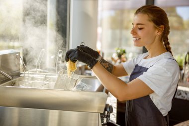 Kızartma makinesi ve buhar aletleriyle donatılmış çağdaş bir mutfakta yemek hazırlama konusunda uzman bir şef.