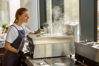 Yetenekli bir barista lezzetli içecekler yapmak için şık bir kafede buharlı tencereyi ustalıkla kullanır.