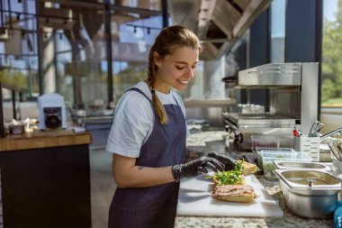 Yetenekli bir şef, şık ve kaliteli bir mutfakta lezzetli bir sandviç hazırlar.