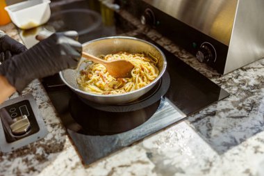 Yetenekli bir şef, modern bir mutfakta özenle pişirilmiş makarna pişiriyor ve güzel bir şekilde yemek pişirme sanatını sergiliyor.