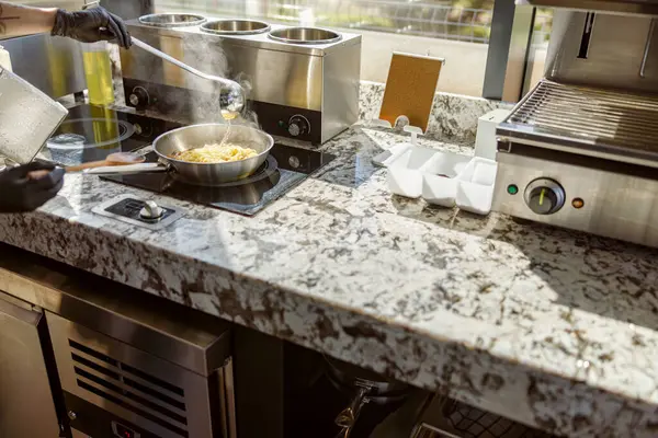 Yetenekli bir şef modern bir mutfakta şık ve zarif bir granit tezgahta lezzetli bir yemek hazırlamakla meşgul.