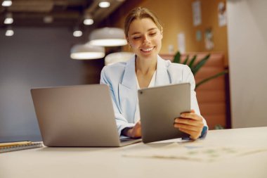 Motive olmuş genç bir profesyonel, modern ve şık bir çalışma alanındaki son teknolojiyle aktif olarak meşgul.