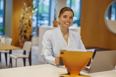 Sıcak ve arkadaş canlısı bir resepsiyonist, müşterileri çağdaş ve şık bir çalışma alanına girerken karşılıyor.