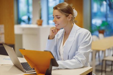 Odaklanmış profesyonel bir kadın laptopunu modern bir çalışma alanına yerleştiriyor ve üretkenliğini gösteriyor..