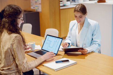 Modern bir ofis ortamında bir masada birlikte çalışan iki yetenekli profesyonel işbirliği üzerine odaklanmıştır.