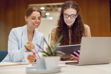 İki profesyonel, yaratıcı ve şık bir ofiste dizüstü bilgisayarla çalışırken yenilikçi fikirleri paylaşıyorlar.