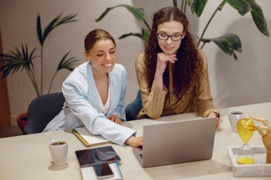 Modern bir ofiste dizüstü bilgisayarla iş birliği yaparken iki profesyonel üretken bir tartışmaya girişti.