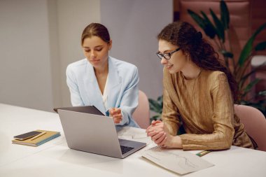 İki yetenekli profesyonel, modern bir ofiste dizüstü bilgisayarın etrafında üretken bir tartışma içinde, fikir alışverişinde bulunuyorlar.