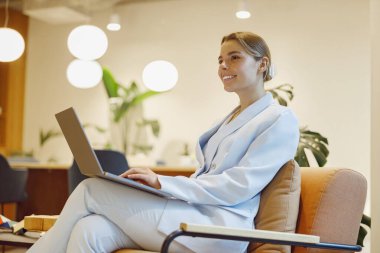 Kendini işine adamış profesyonel bir kadın modern ve şık bir ofis ortamında dizüstü bilgisayarı üzerinde çalışıyor.