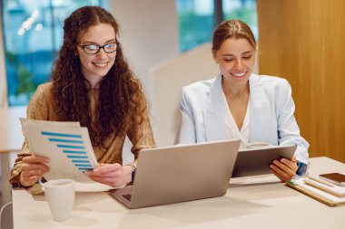 İki kadın, dijital cihazlarındaki raporları ve verileri aktif olarak gözden geçirirken oldukça üretken bir tartışmaya giriştiler.
