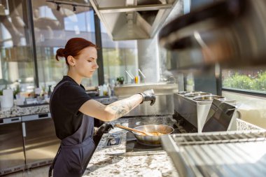 Çok yetenekli bir şef, doğal ışıkla dolu güzel tasarlanmış çağdaş bir mutfakta ustaca yemek pişirir.